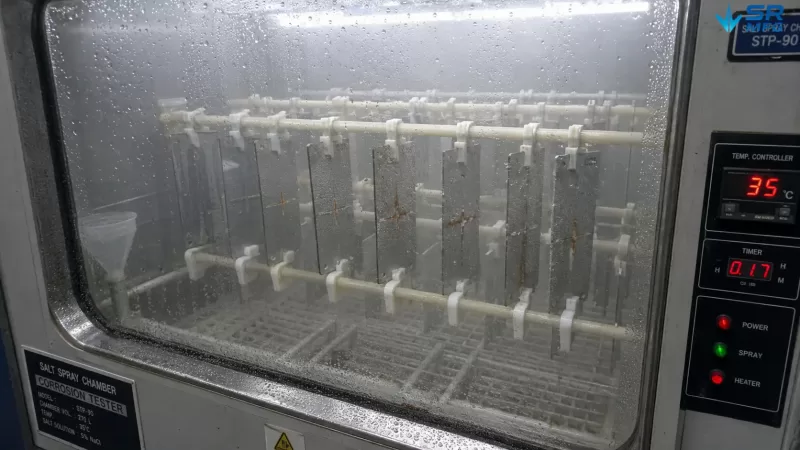Salt spray test chamber interior with 2mm coated steel sheet test coupons mounted on racks during ASTM B117 corrosion resistance testing