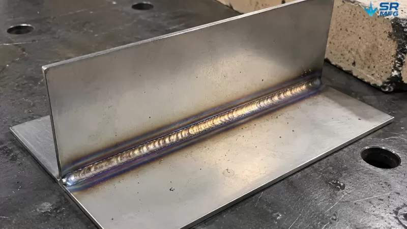 TIG-welded 2mm stainless steel sheet joint showing heat discoloration bands ranging from straw yellow to purple blue around the weld bead