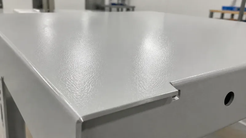 Close-up photograph of a powder-coated steel enclosure panel showing smooth semi-gloss texture and uniform color coverage