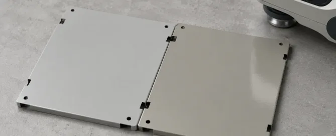Two sheet metal panels with different gray paint shades placed side by side showing a visible color mismatch