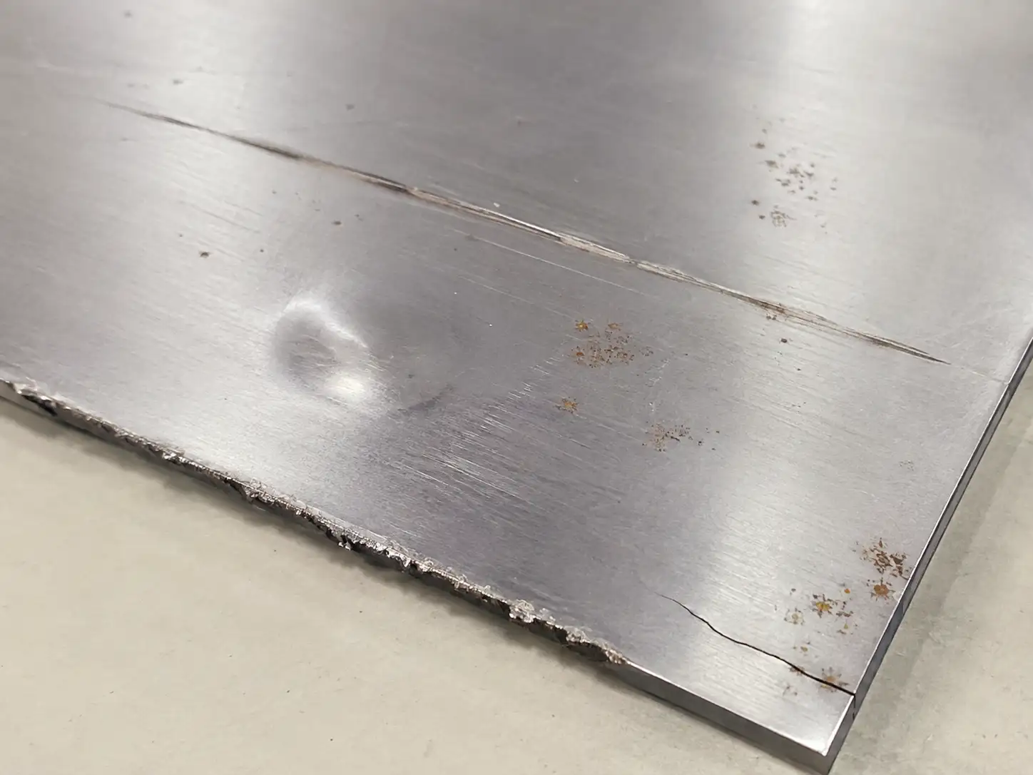 Cold-rolled carbon steel sheet showing deep scratches, dents, edge burrs and rust defects